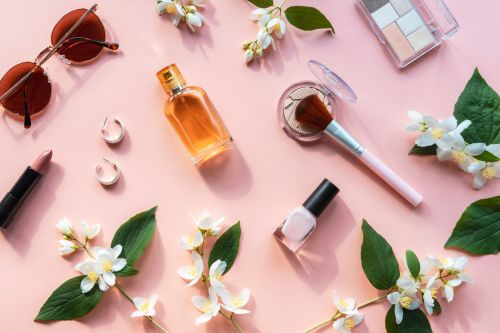 Diverse Kosmetikprodukte und Blätter auf rosa Untergrund